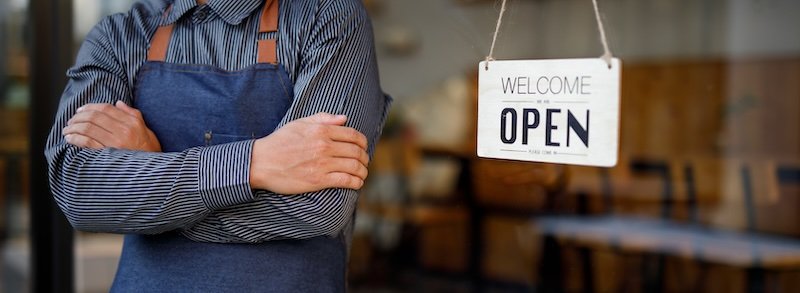 Close up of Store owner turning open sign broad through the door glass and ready to serve. hotel service, cafe-restaurant, retail store, small business owner concept