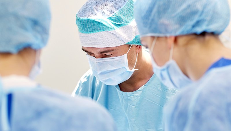 surgery, medicine and people concept - group of surgeons at operation in operating room at hospital