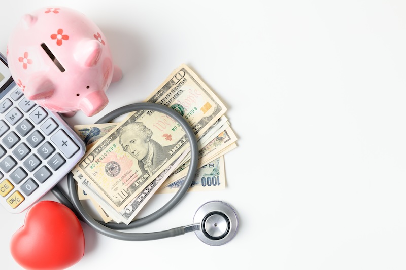 Stethoscope on banknote and piggy bank on white background, saving money for health insurance concept